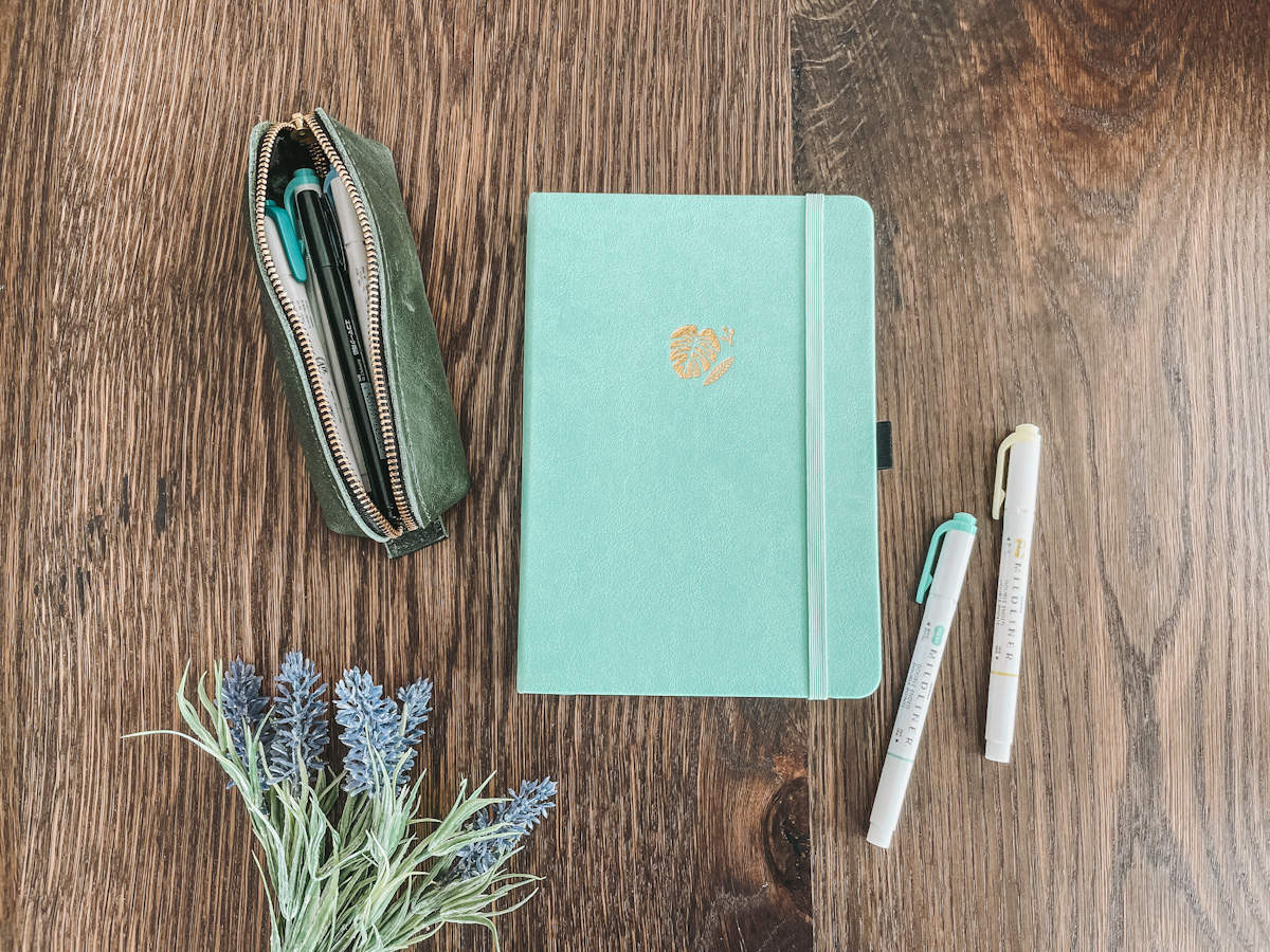 bullet journal supplies spread out over a wooden tabletop