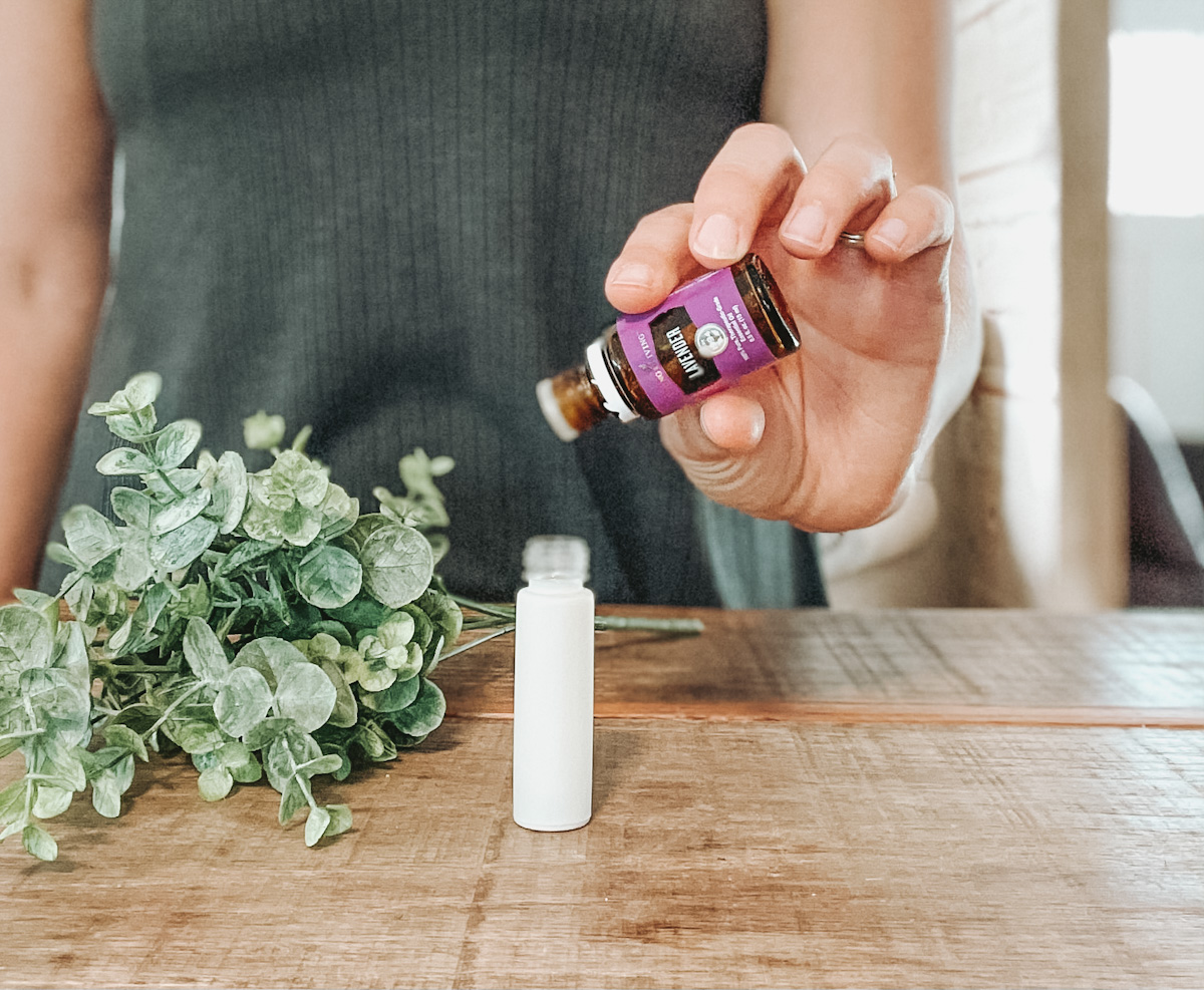 woman holding lavender essential oil and putting drops in a white roller bottle for bug bite relief