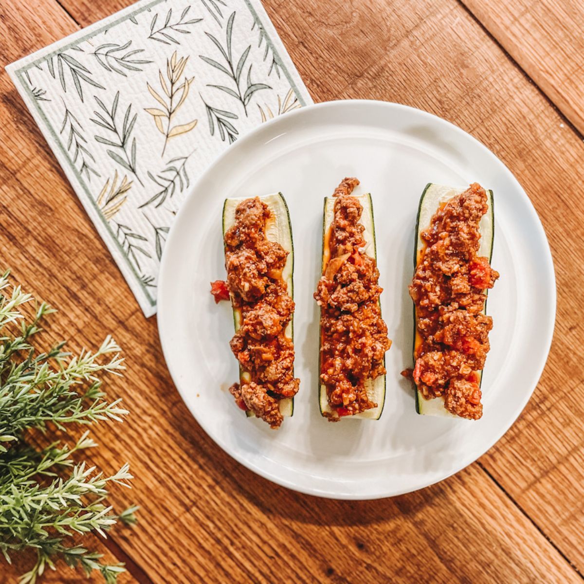 three italian zucchini boats on white plate and wooden counter top