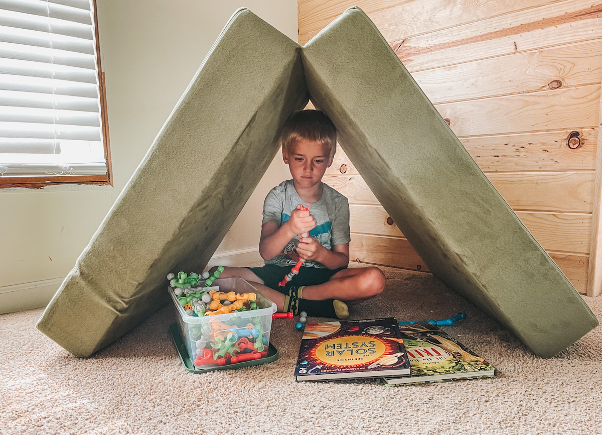 kid in a fort doing quiet time with open ended toys
