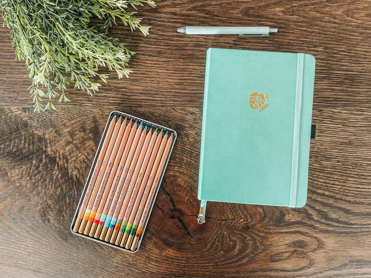 best homeschool planner for moms laid out on a wood tabletop with a pen and colored pencils
