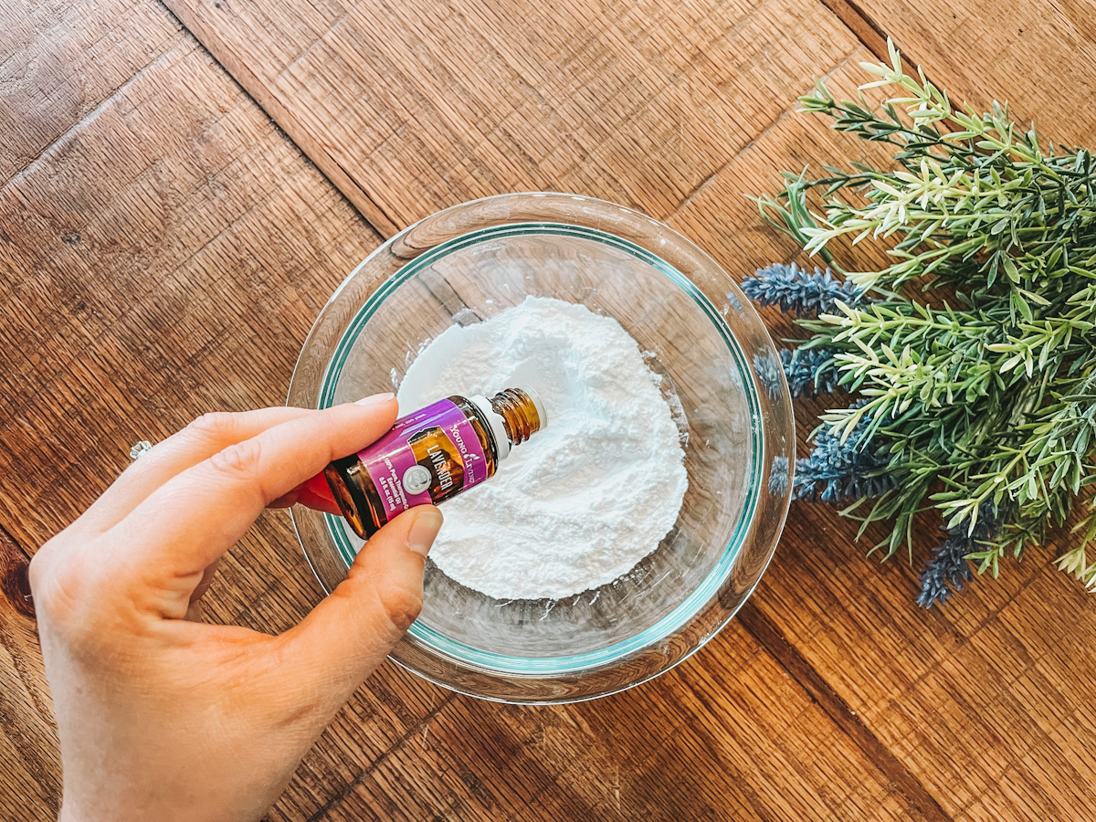 lavender essential oil being dropped into a bowl of dry ingredients