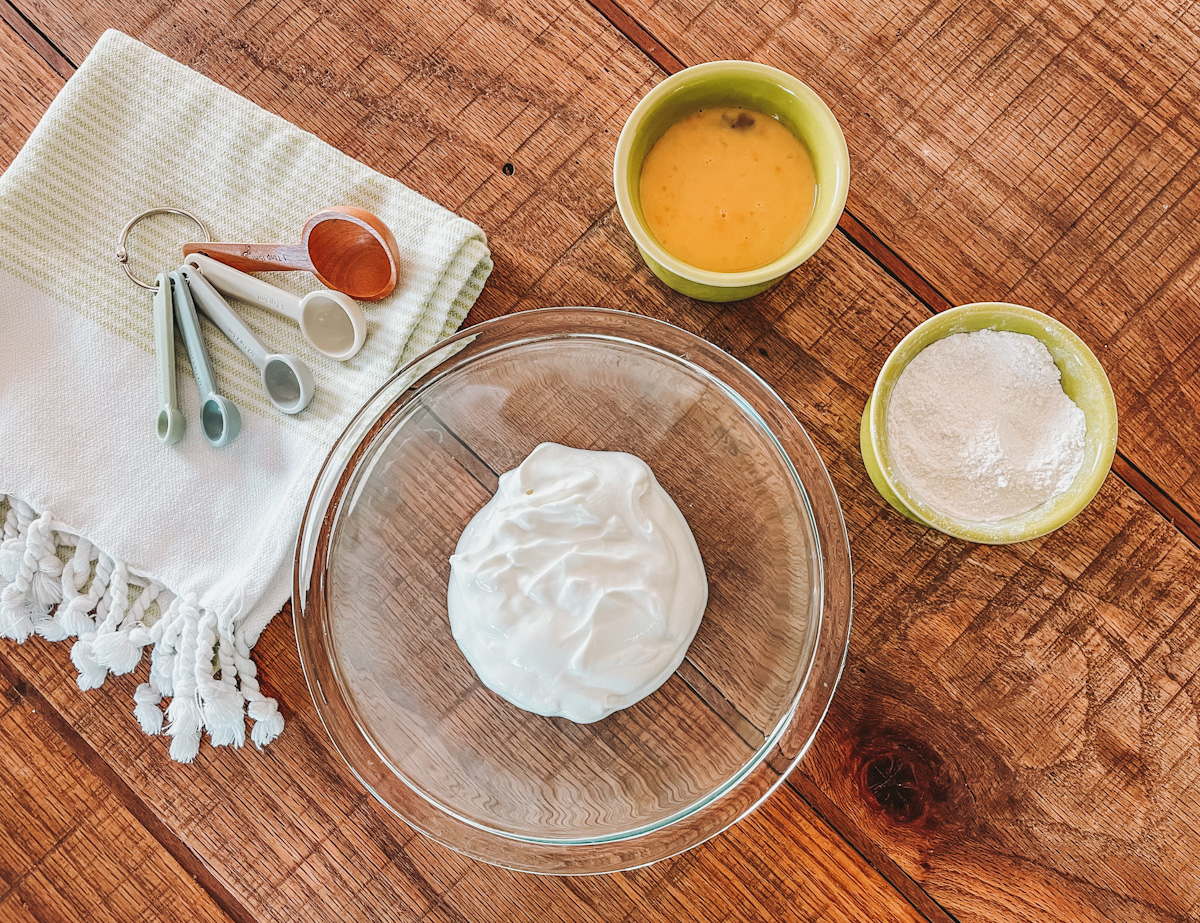 Greek yogurt pancake ingredients prepped in separate bowls on a wooden countertop