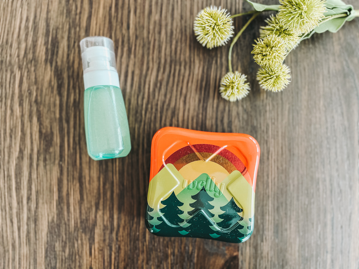 refillable first aid kit and homemade insect repellent for kids laying on a wood surface