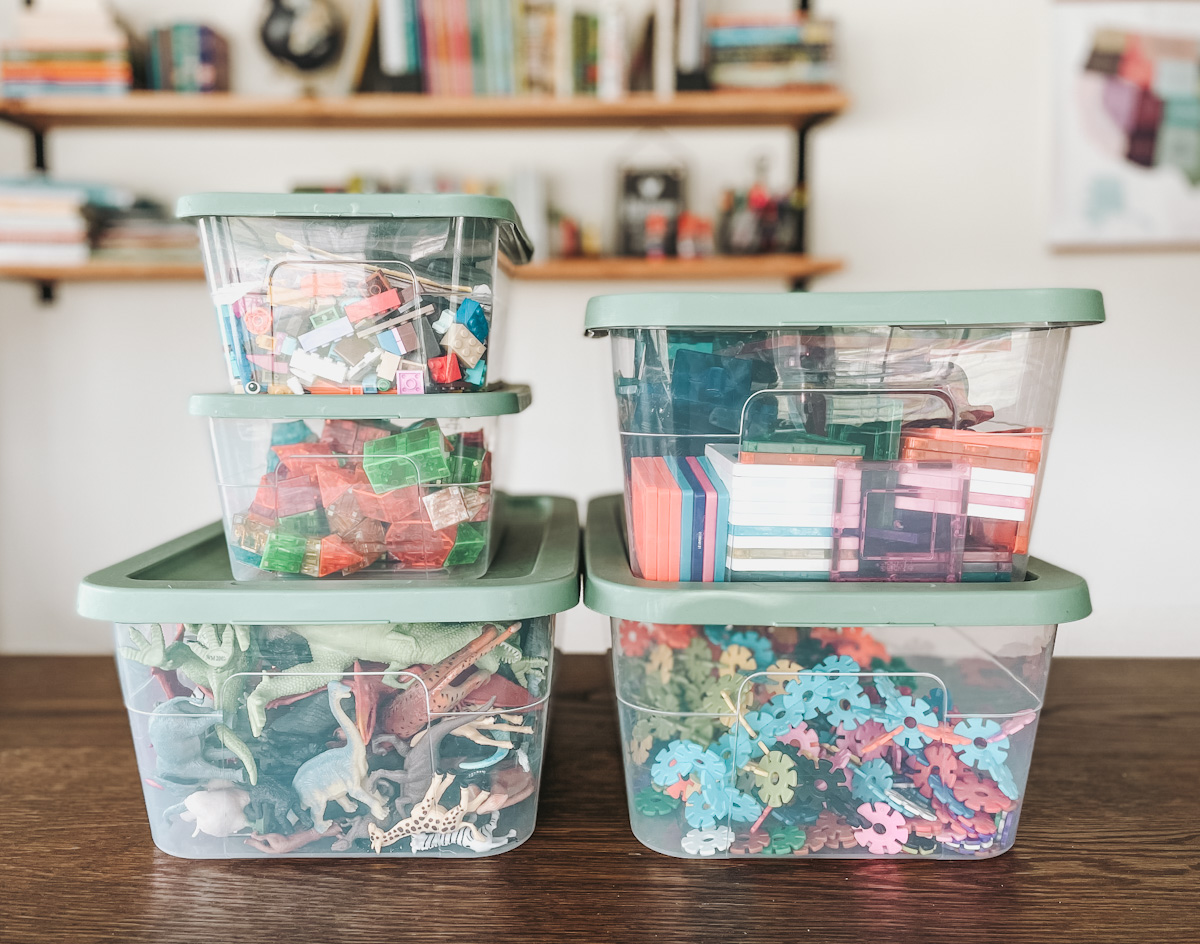 plastic storage bins stacked up with open ended toys inside of them as a toy storage solution