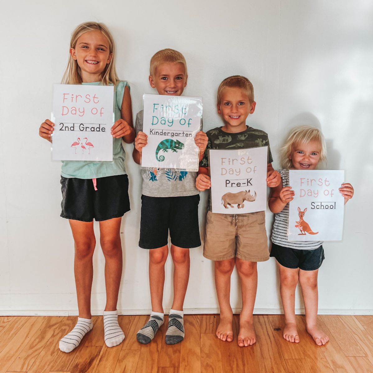 four kids standing in a row from oldest to youngest holding up their first day of homeschool signs
