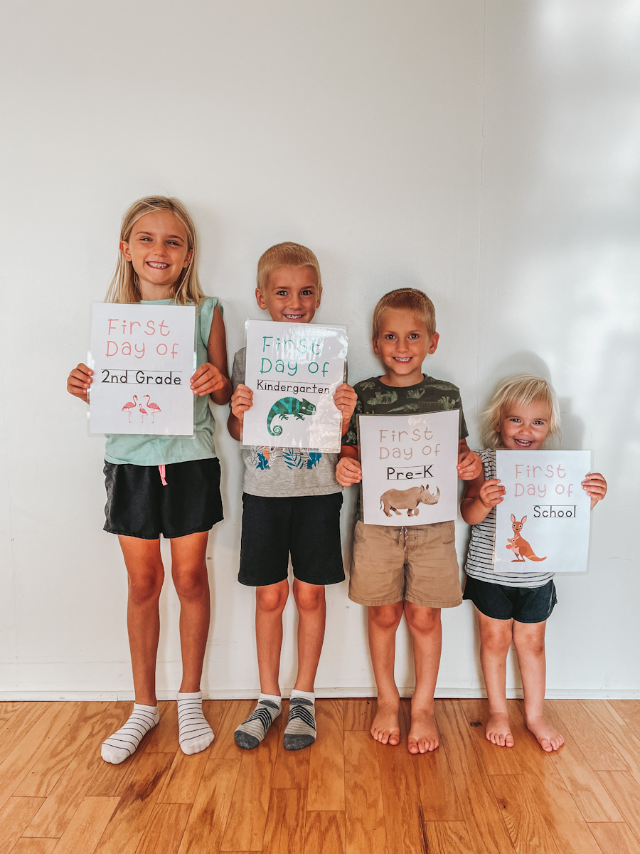 four kids standing in a row holding up their first day of homeschool signs