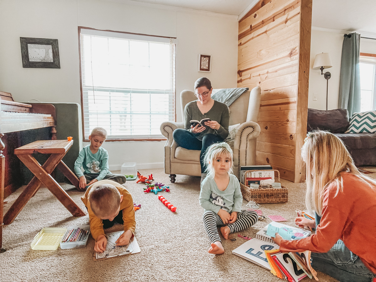 homeschool mom and four kids sitting around a living room doing their morning basket time
