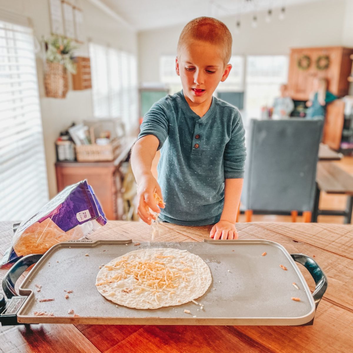 boy putting cheese on a tortilla to make a quesadilla for a simple homeschool lunch idea