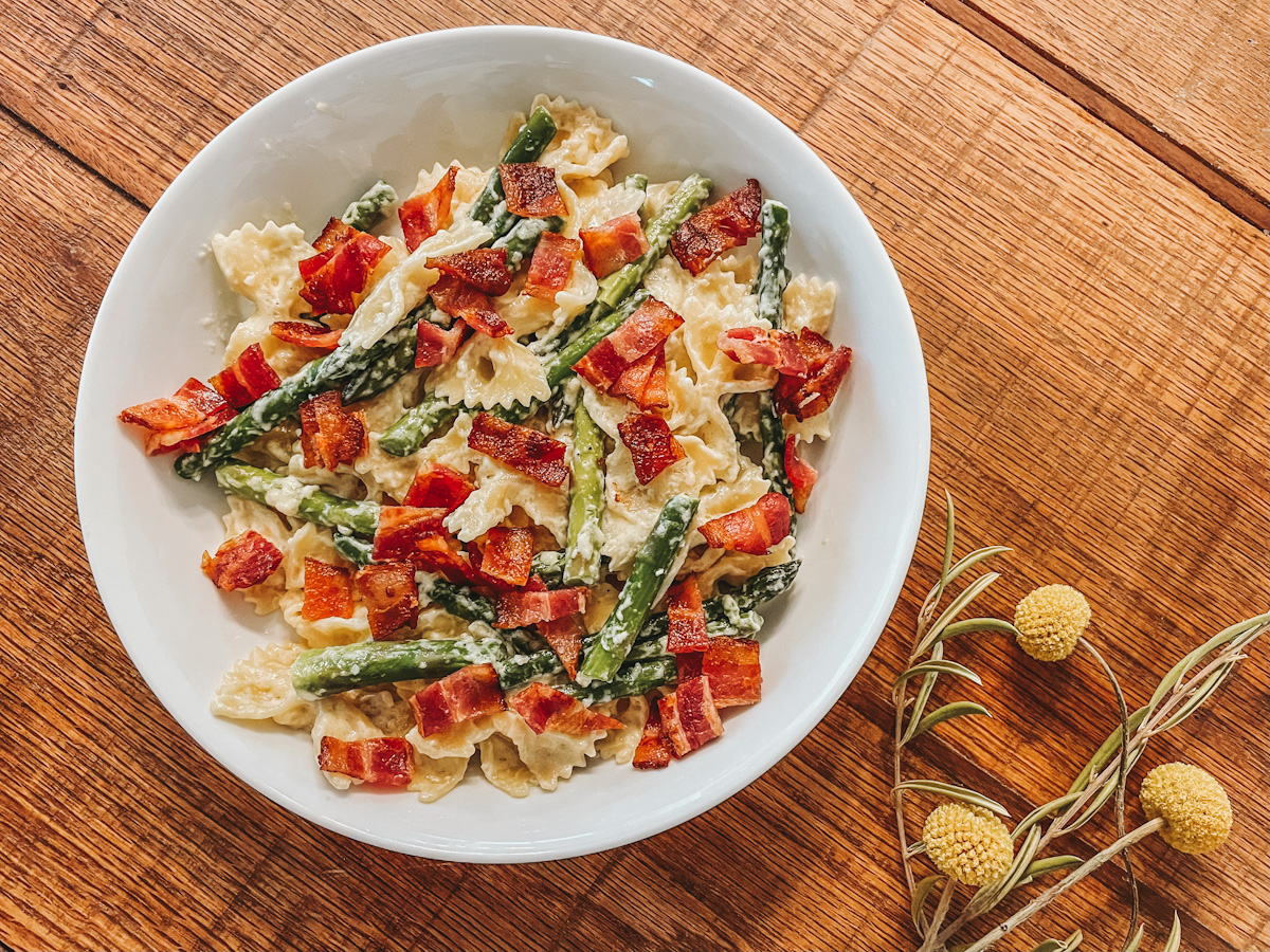 white bowl filled with creamy pasta with fresh asparagus and bacon