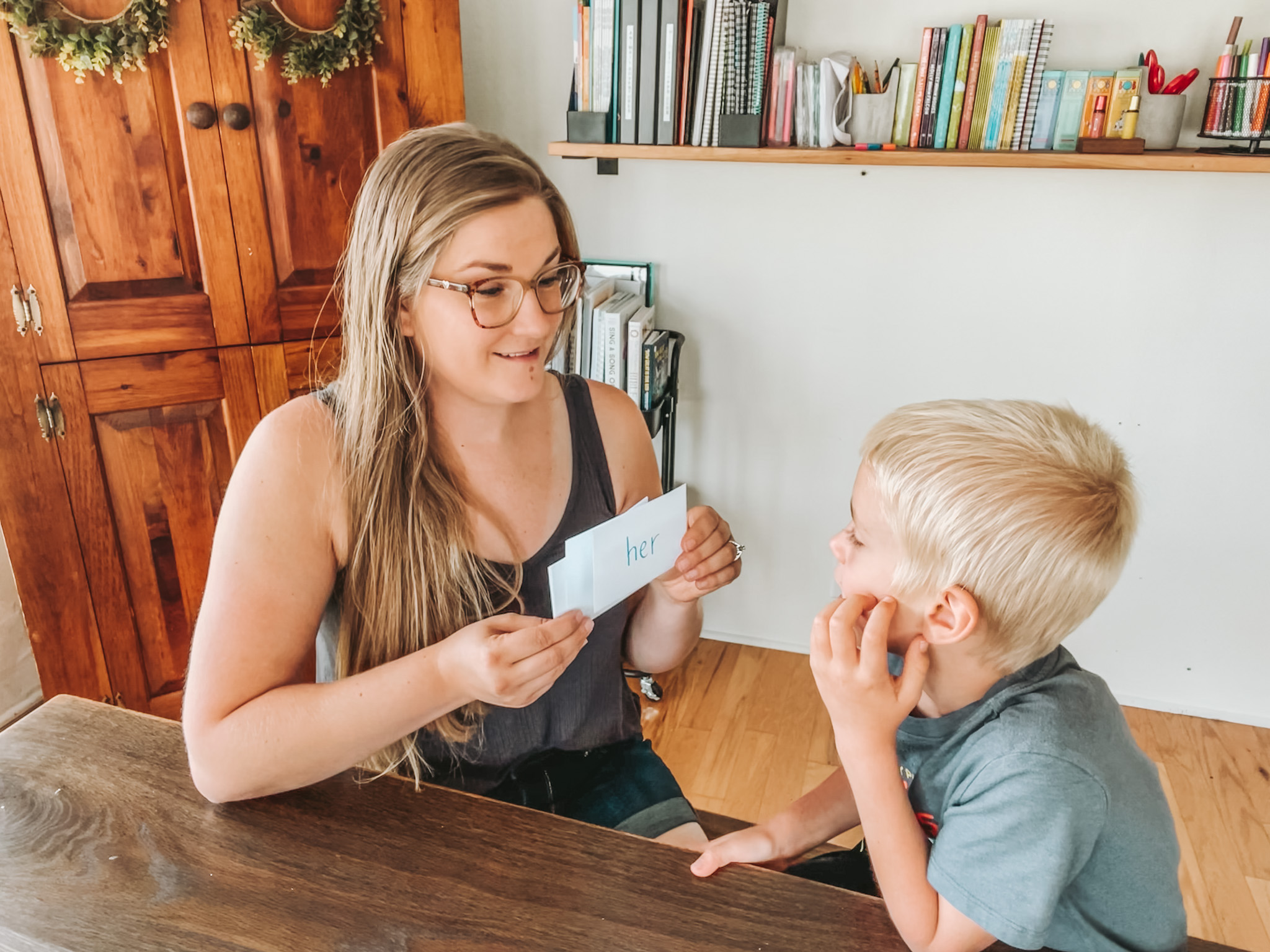 homeschool mom holding up flash cards with popcorn words written on them for her kindergarten son to learn